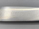 a close up of a knife on a table with a gray background