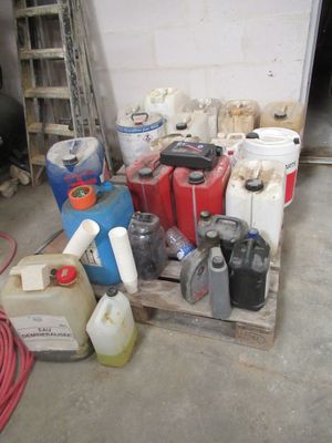 une pile de bidons d'essence posés sur une palette dans un garage