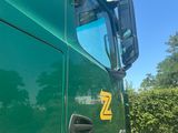 a green semi truck with a yellow z logo on it