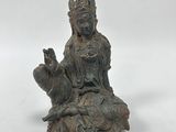 an old statue of a woman sitting on top of a rock