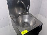 un évier en acier inoxydable dans le coin d'une toilette publique