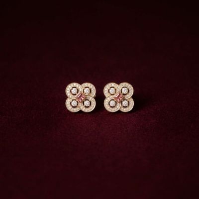 a pair of diamond and gold earrings on a maroon background