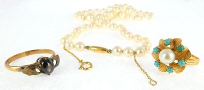 three rings, a necklace, and a ring with pearls on a white surface