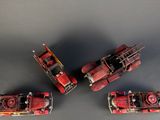 three red toy fire trucks sitting next to each other on top of a table