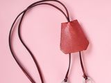 a red leather bag with two metal rings on a pink background