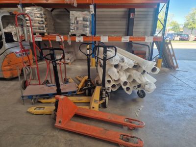 a fork truck with a pallet and a stack of pallets in a warehouse