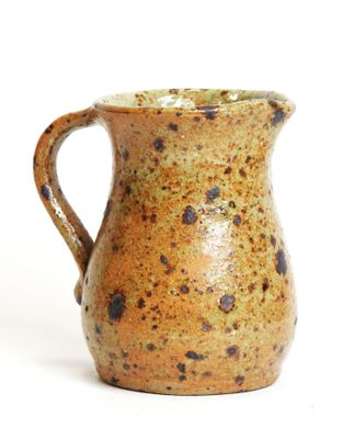 a brown and black pitcher sitting on a white surface