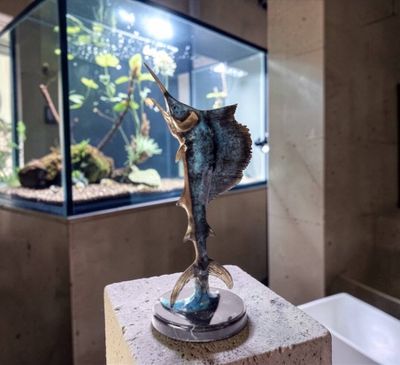 a statue of a fish on a pedestal in front of a fish tank