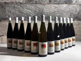 bottles of wine are lined up on a table in front of a stone wall