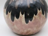 a black and pink vase sitting on a white surface