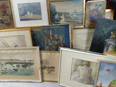 de nombreux tableaux encadrés posés par terre dans une pièce