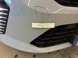the front end of a silver car with a sticker on it ' s bumper