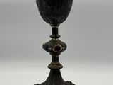 un gobelet ancien noir et or posé sur une table blanche