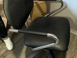une personne debout à côté d'une chaise noire dans une pièce