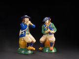 two figurines of two men sitting on top of each other