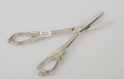 pair of silver scissors on a white surface with a price tag on it