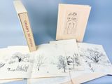 un livre ouvert posé sur une table, à côté d'une pile de dessins