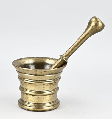 un mortier et un pilon anciens en laiton sur fond blanc