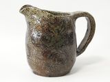 une cruche marron et noire posée sur une surface blanche