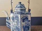 a blue and white teapot sitting on a wooden table