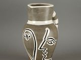a vase with a face painted on it sitting on a table