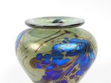 un vase bleu et vert posé sur une surface blanche