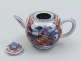 a small teapot with a lid and a small cup