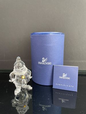 une figurine en verre représentant un bonhomme de neige, posée à côté d'une boîte bleue