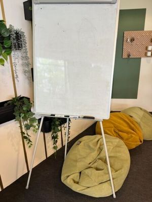 un tableau blanc posé sur un trépied dans une pièce