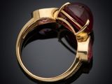 a close up of a gold ring with a red stone