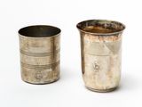 two silver cups sitting next to each other on a white surface