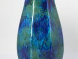 a blue vase with a green base on a white background