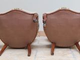 pair of leather chairs with arms and legs on wooden legs
