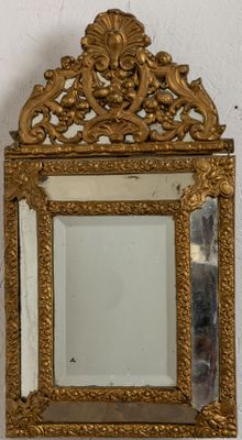 un miroir doré accroché au mur, avec un cadre doré