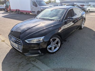 L'Audi noire est garée sur un parking, à côté d'un camion.