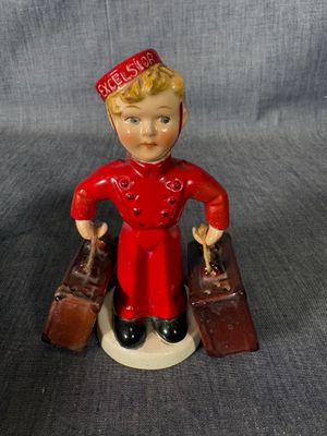 une figurine représentant un garçon avec des valises posées sur une table
