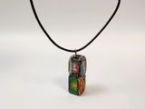 a close up of a necklace on a black cord with a picture on it