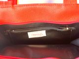 a red purse with a black handle on a white table
