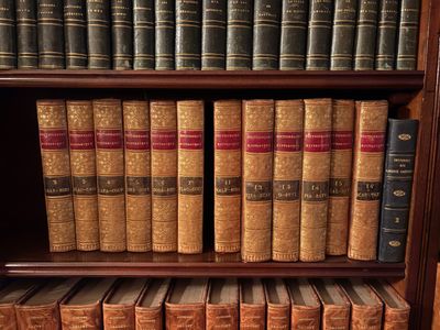 de nombreux livres anciens sur une étagère en bois dans une bibliothèque