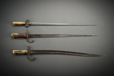 three old swords are displayed on a gray surface with a black background
