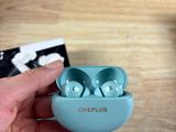 une personne tenant dans sa main une paire d'AirPods OnePlus bleus