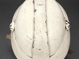 an old white helmet with a leather strap on a black background