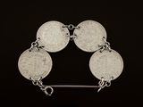 a close up of a silver bracelet with five coins on it