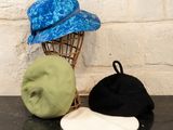 trois chapeaux posés sur une table à côté d'un porte-chapeaux