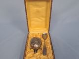 un petit objet en argent dans une boîte en bois, avec une cuillère et un repose-cuillère