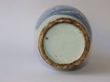 a blue and white vase with a brown rim