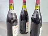 three bottles of wine are lined up on a table