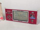 a small electronic game console next to a box of candy