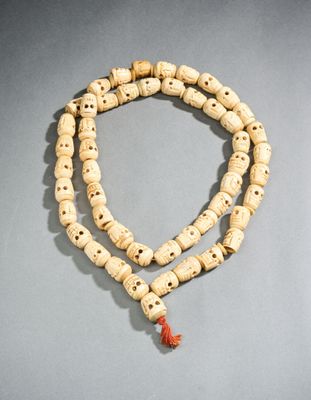 un gros plan d'un collier de perles en bois posé sur une surface grise