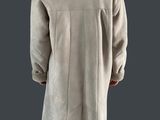 Une femme en blouse blanche se tient debout sur un fond gris.